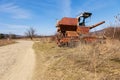 Selective focus on dirt road and abandoned harvester. Broken rust agricultural equipment