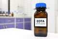 Selective focus of EDTA liquid chemical compound reagent solution in dark glass bottle inside a chemistry laboratory.