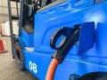 Selective focus at Electric forklift charging inside of the warehouse. With pallet of white small bag blurred at the background.