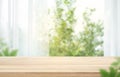 Selective focus.Empty of wood table top on blur of curtain with window and green from garden background Royalty Free Stock Photo
