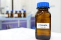 Selective focus of ethanol or ethyl alcohol brown amber glass bottle inside a laboratory. Blurred background with copy space.