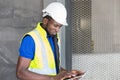Selective focus at face of Black African foreman at building construction site, wearing protective hat and safety equipment while