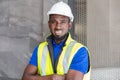 Selective focus at face of Black African foreman at building construction site, wearing protective hat and safety equipment, smile