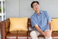 Selective focus at face of old senior Asian man sitting at sofa touching knee and legs suffer from the pain and injury.