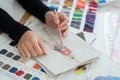 Selective focus on fashion designer hand, holding pencil, sketching creative clothes on paper, with fabric and threads color chart Royalty Free Stock Photo