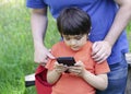 Selective focus father teaching his son using smart phone, Crop shot Dadplaying game with his little boy in the park, Child lookin