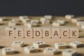 Focus of feedback inscription on cubes surrounded by blocks with letters on wooden surface isolated on black