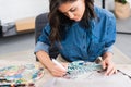 selective focus of female fashion designer painting on jacket at working table in clothing