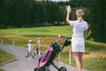 selective focus of female golf player in cap and white polo with golf gear greeting friends