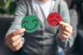 Selective focus of female hands holding happy and angry face paper sit on sofa. Feedback rating, emotional intelligence, balance