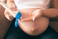 Pregnant female keeping cream and applying it on big belly Royalty Free Stock Photo