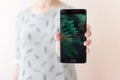 Young woman holding mobile phone with copy space, showing her black blank screen to the camera. People and technology. Royalty Free Stock Photo