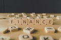 Focus of finance inscription on cubes surrounded by blocks with letters on wooden surface isolated on black