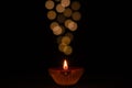 Selective focus on flame of clay diya lamp lit on dark background