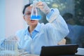 Focus on a flat-bottomed flask in the hand of a chemist inspecting the chemical reaction taking place in blue solution