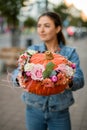 selective focus on flowers arrangement in pumpkin in women hands. Royalty Free Stock Photo