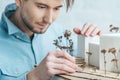 selective focus of focused architect looking at self made building model