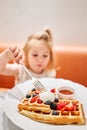 Selective focus in the foreground. Happy 3 year old girl eat. Breakfast in cafe. Classic Viennese waffles with ice cream Royalty Free Stock Photo