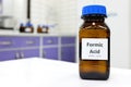 Selective focus of Formic acid solution in brown amber bottle. Blur white laboratory backdrop with copy space.