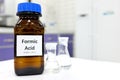 Selective focus of Formic acid solution in brown amber bottle. Blur white laboratory backdrop with copy space.