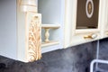 Selective focus fragment of beige wooden cabinetry kitchen carved detail. Carved decorative detail. Wooden pilasters