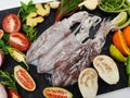 Selective Focus of fresh raw Loligo Squid Loligo Duvauceli decorated with curry leaves, tomato, lemon slice, and herbs on a Royalty Free Stock Photo