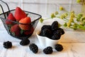 Selective focus of fresh strawberries and blackberries on white table as a background.