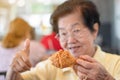 Selective focus of fried chicken, Asian elderly women are eating fried chicken. In the restaurant, lift the thumb. Concept of agin Royalty Free Stock Photo