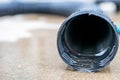 Selective focus on the front opening of a residential sump pump discharging water from the end of a flexible black hose