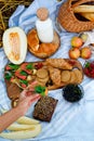 Selective focus. The girl takes a sandwich. Summer picnic with bruschettas with salmon, berries, melon on a wooden board and a Royalty Free Stock Photo