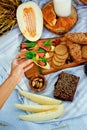 Selective focus. The girl takes a sandwich. Summer picnic with bruschettas with salmon, berries, melon on a wooden board and a Royalty Free Stock Photo