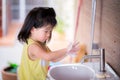 Selective focus. Girl wash their hands in the white sink. Child rub their hands with white soap bubble.