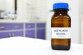 Selective focus of glacial Acetic acid solution in brown amber bottle. Blur white laboratory backdrop with copy space. Royalty Free Stock Photo