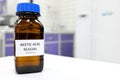 Selective focus of glacial Acetic acid solution in brown amber bottle. Blur white laboratory backdrop with copy space. Royalty Free Stock Photo