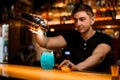 selective focus on glass with iced blue cocktail on bar and bartender pouring liquid into it from shaker Royalty Free Stock Photo