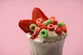 Selective focus of glass of milkshake with ice cream, cut strawberries and candies