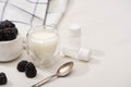 Selective focus of glass of yogurt, teaspoon, containers with starter cultures and sugar bowl with blackberries Royalty Free Stock Photo