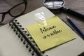 Selective focus of glasses, pencil, magnifying glass, notebook and yellow paper written with Patience is a virtue Royalty Free Stock Photo