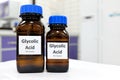 Selective focus of glycolic acid liquid solution in dark brown glass bottle in a white chemistry laboratory background.