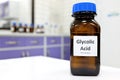 Selective focus of glycolic acid liquid solution in dark brown glass bottle in a white chemistry laboratory background.