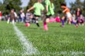 Selective focus on ground level view of soccer field center line with defocused youth girls in background Royalty Free Stock Photo