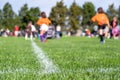 Selective focus on ground level view of soccer field center line with defocused youth girls in background Royalty Free Stock Photo