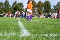 Selective focus on ground level view of soccer field center line with defocused youth girls in background Royalty Free Stock Photo
