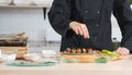 Selective focus on hand of anonymous young chef man, in black uniform, garnishing seaweed on japanese food called takoyaki Royalty Free Stock Photo