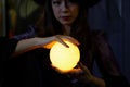 Selective focus on hand of Asian girl dressed as a witch holding a magic crystal bal Royalty Free Stock Photo