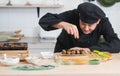 Selective focus on hand of Asian young handsome chef man, in black uniform, garnishing seaweed on japanese food called takoyaki Royalty Free Stock Photo