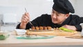 Selective focus on hand of Asian young handsome chef man, in black uniform, garnishing teriyaki sauce on japanese food called tako Royalty Free Stock Photo