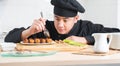 Selective focus on hand of Asian young handsome chef man, in black uniform, garnishing teriyaki sauce on japanese food called tako Royalty Free Stock Photo