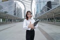 Selective focus on hand of cheerful young Asian businesswoman looking confident and showing thump up sign in the city background.