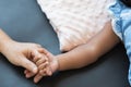 Selective focus on hand of cute African little newborn 7 months old baby girl with black curly hair holding her mother finger Royalty Free Stock Photo